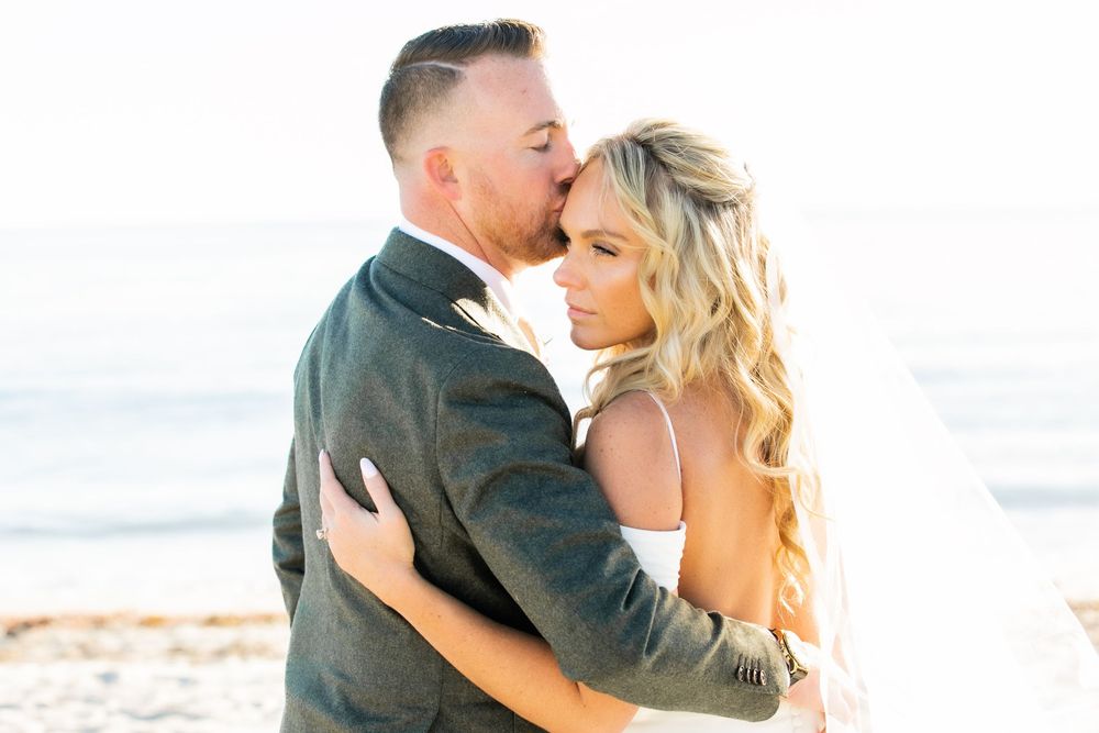 Groom kissing bride on temple on a beach in Cape Cod