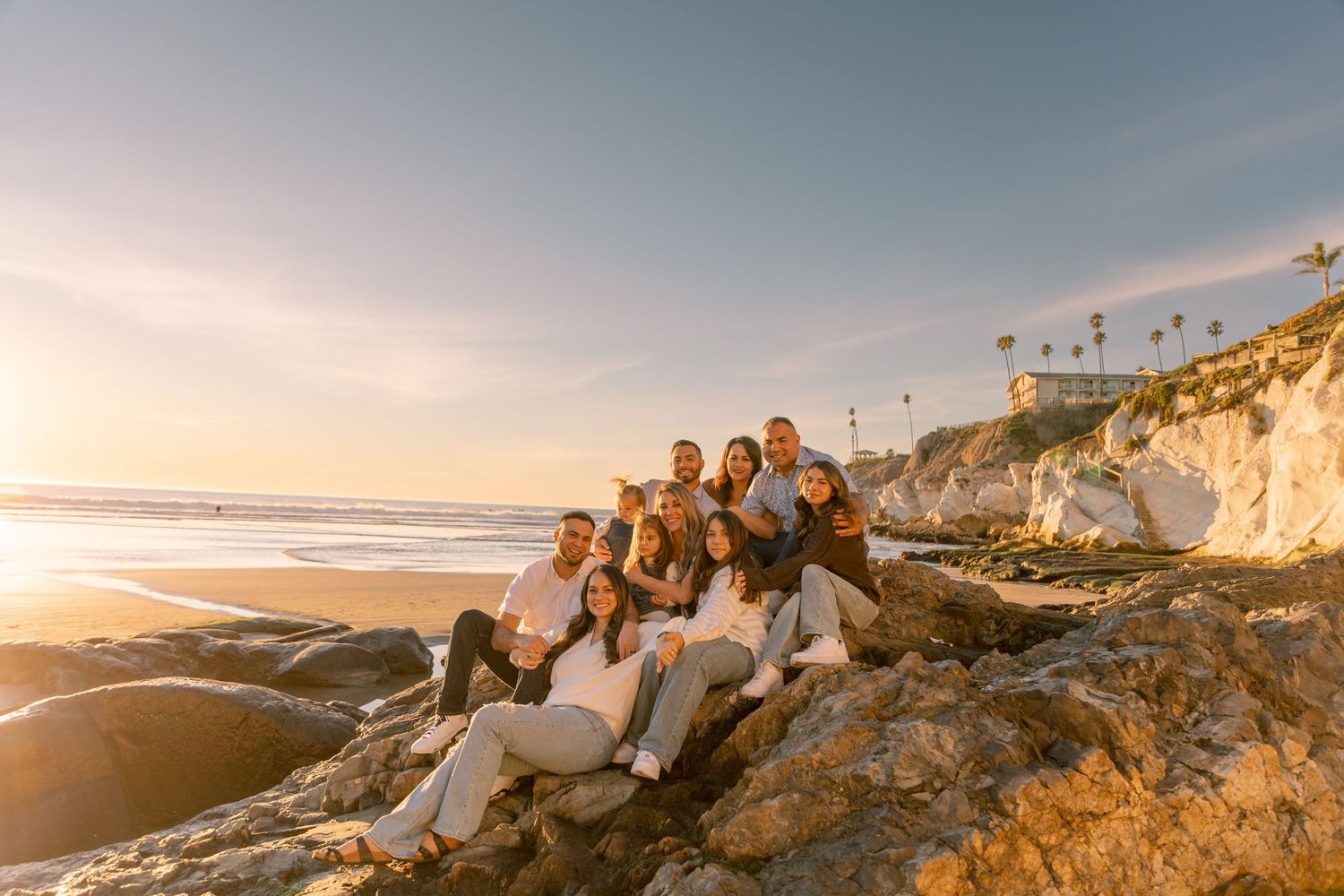 Group gathered together on a sandy beach with white rock formations in the background during golden hour.
