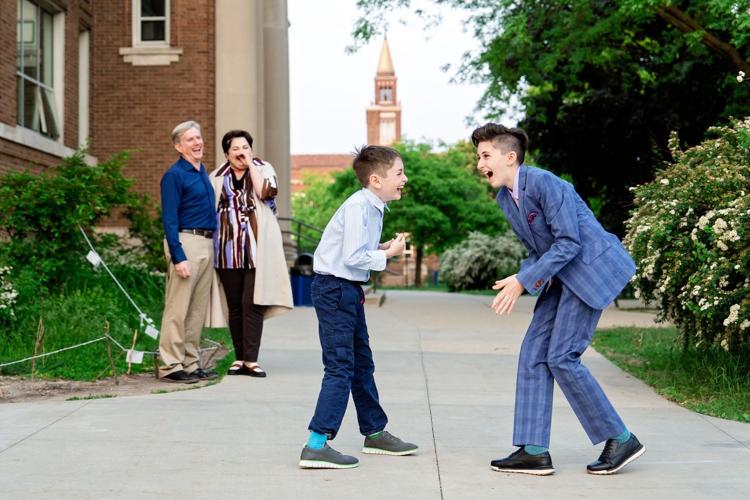 Family photo with parents in the background laughing at their boys who are playing with each other, taken by Rachel Dickman.