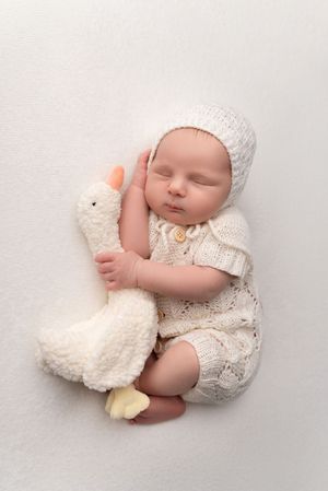 Newborn boy cuddling a goosling, posed on a beanbag