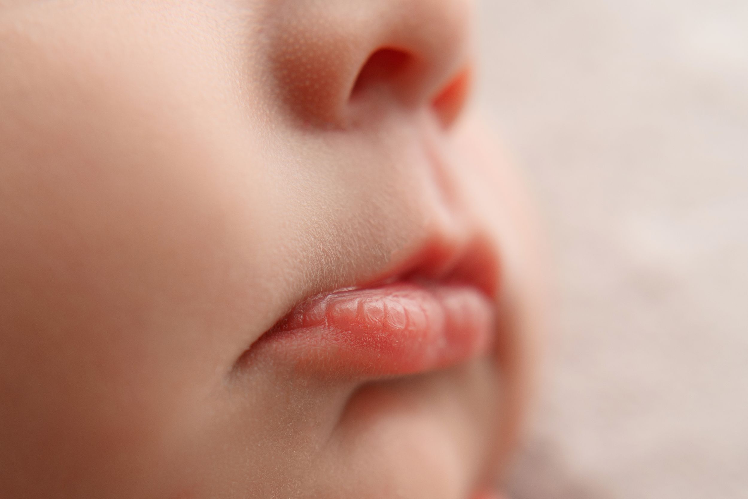 Extreme close-up macro shot of a sleeping newborns delicate lips and nose.