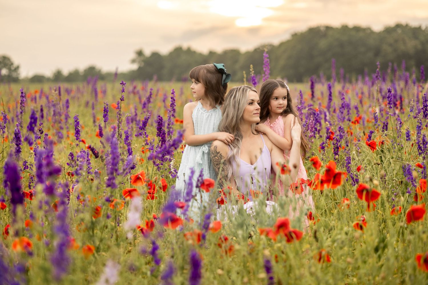 Two children in dresses holding hands in sunset field with horse grazing in background.