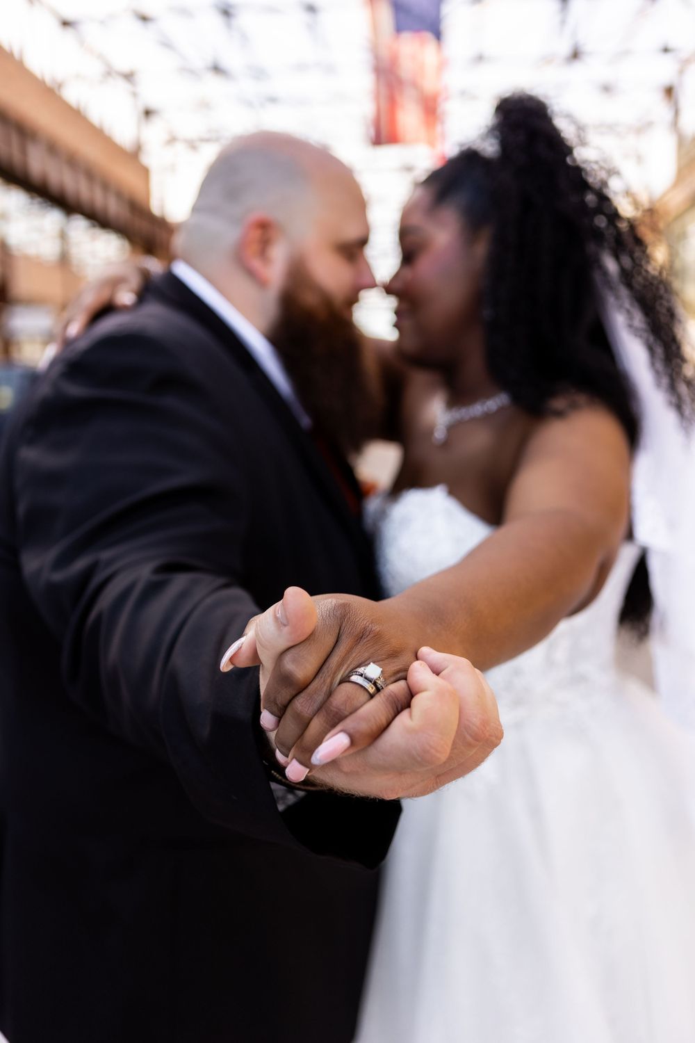 Close-up of newlyweds holding hands showing wedding rings during intimate moment at their wedding ceremony.