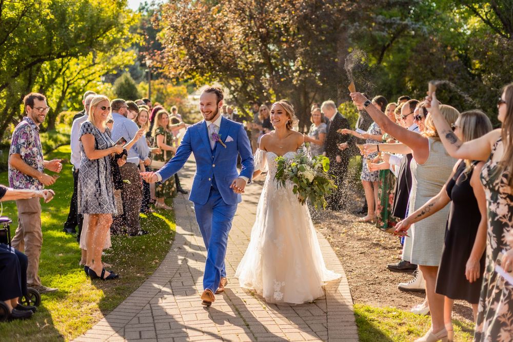 Wedding guests shower the newlyweds with confetti on a sunny garden path during their joyous celebration.