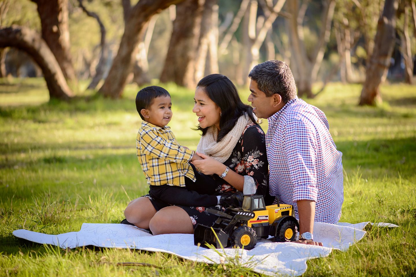Family of three sitting on a blanket in the park - Kelly Chapman Photographer Perth