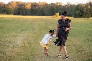 A pregnant mother walking in a field with her young daughter - Kelly Chapman Photographer Perth