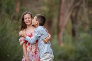 Young boy kissing his sister on the cheek in a bush setting - Kelly Chapman Photographer Perth