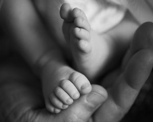 Classic black and white photo of an infants feet in the hands of their father - Kelly Chapman Photographer Perth