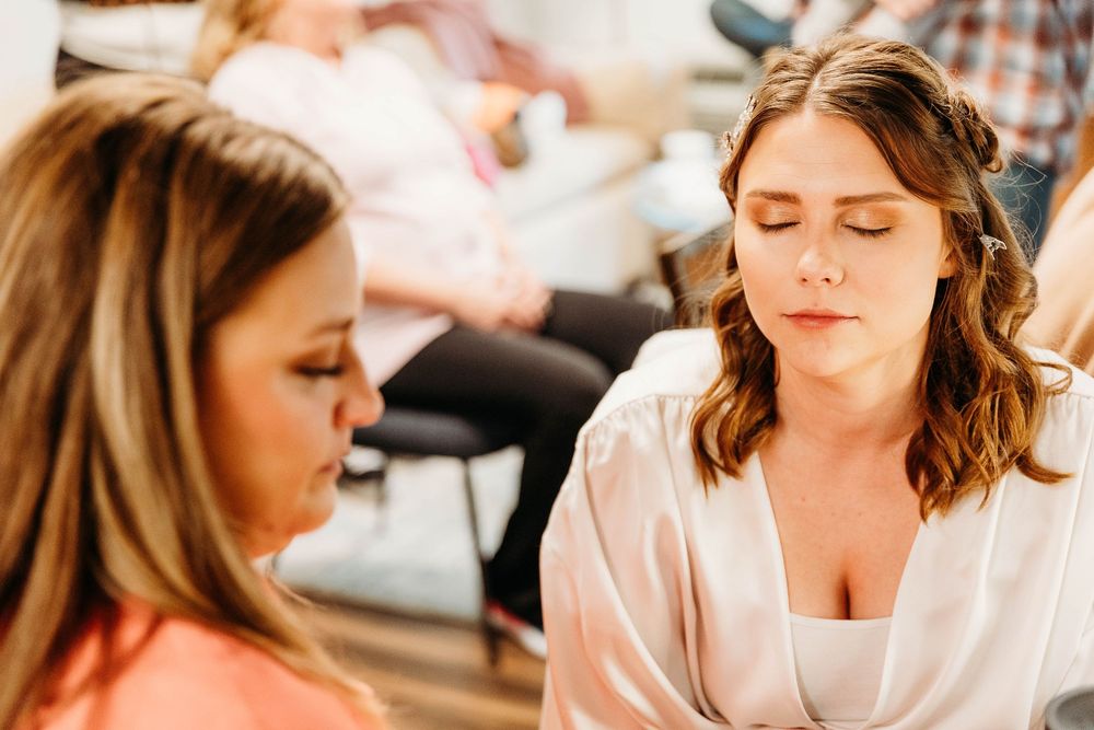 Professional makeup artist applies eyeshadow during a beauty session in warm lighting.