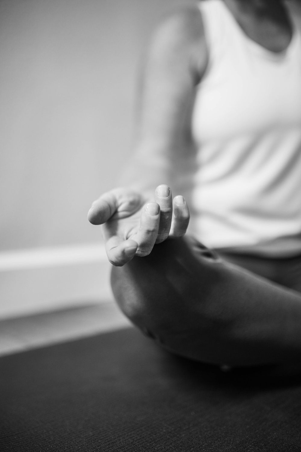 Close-up of hands in meditation pose on dark surface.