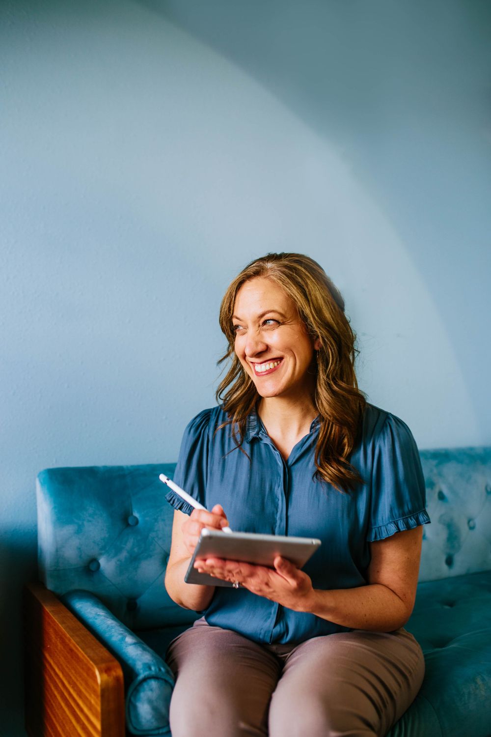 Business casual scene with notebook and blue tufted couch.