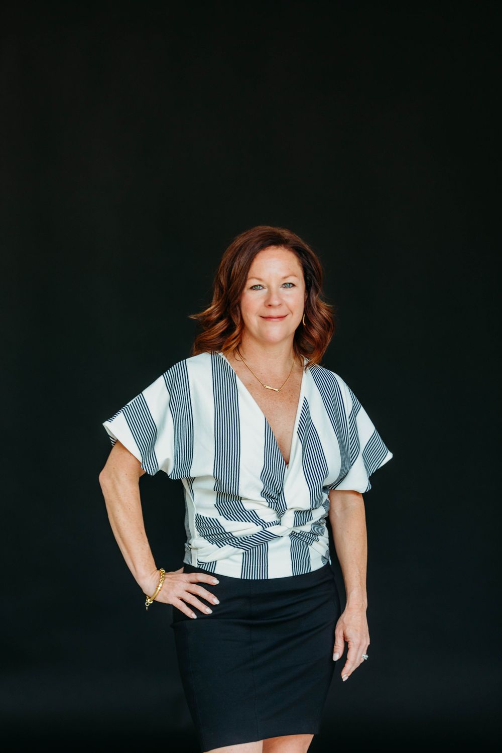A person wearing a blue and white striped top with a black skirt poses against a dark background in multiple shots.
