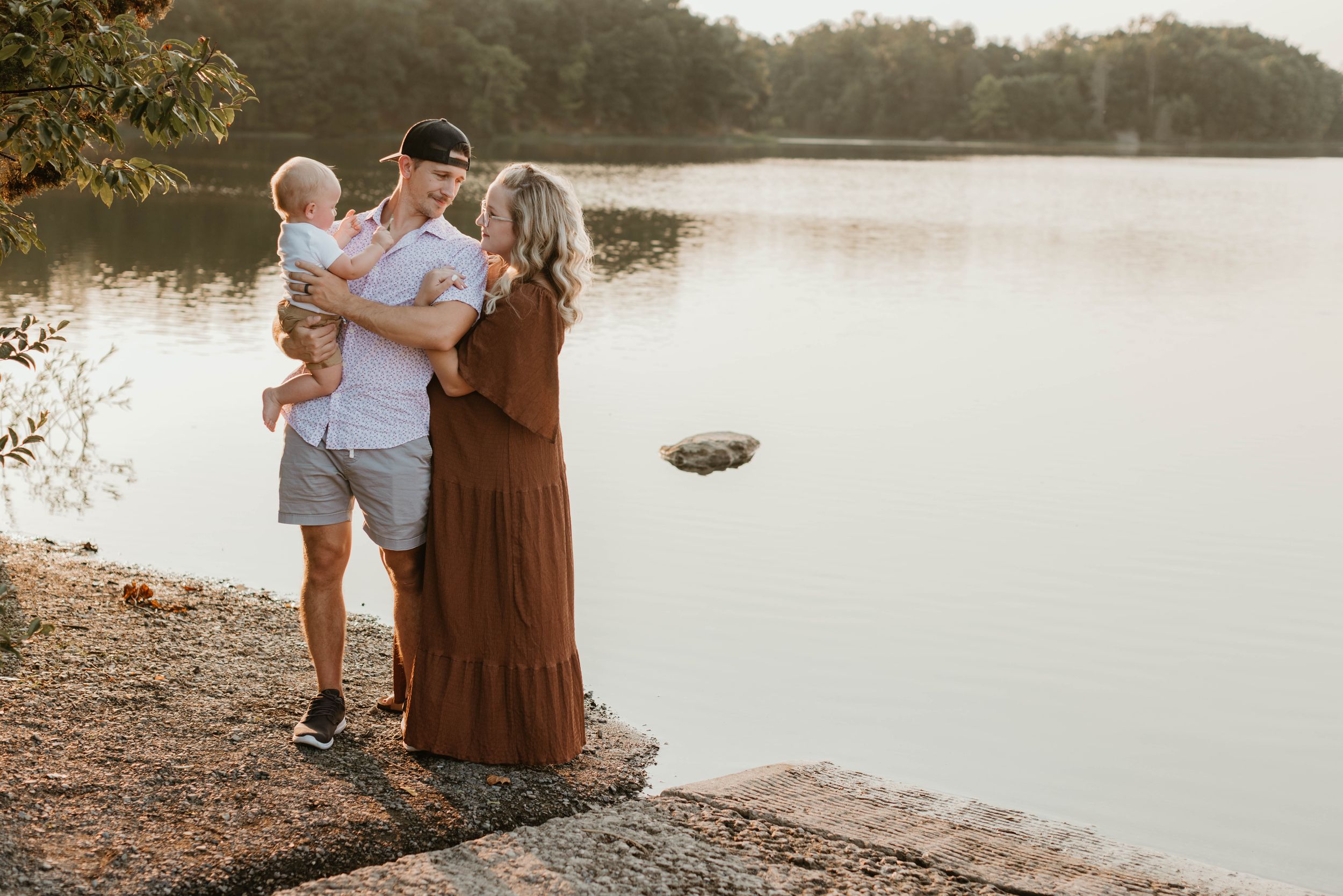 A family enjoys a peaceful moment together by a serene lake at sunset.