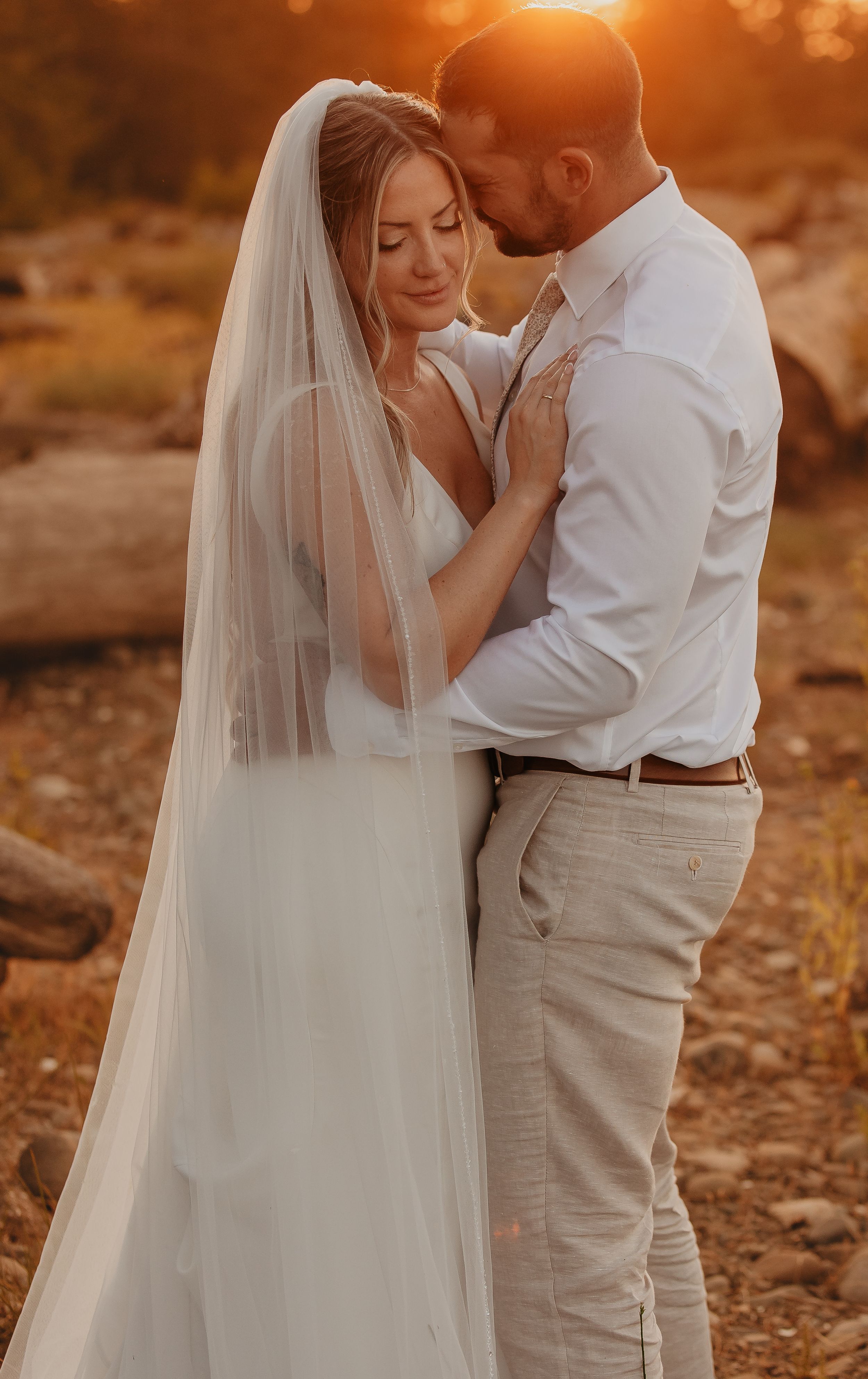 Romantic sunset wedding photos in warm golden light with flowing veil.