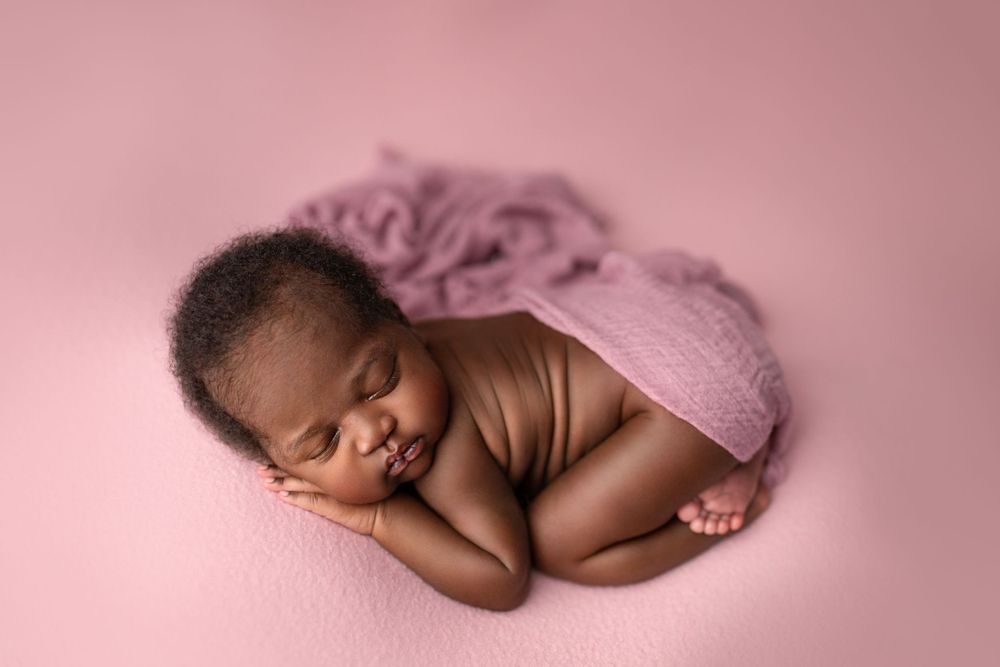 Newborn photography Ipswich and Brisbane – African baby wrapped in purple fabric with floral headband, Springfield Lakes studio portraits fo