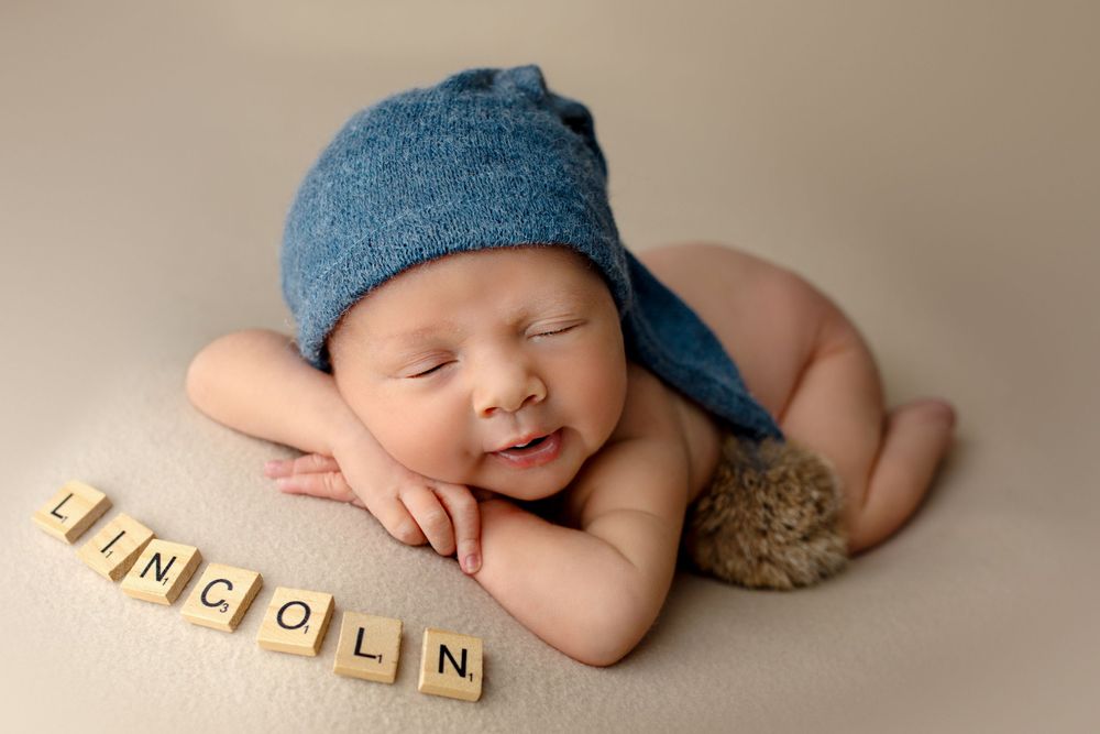 Professional newborn photographer Springfield Lakes – baby boy in blue hat posed with wooden name blocks, affordable newborn portraits for I