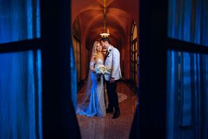 A bride and groom share an intimate moment in a dimly lit hallway with dramatic blue lighting.