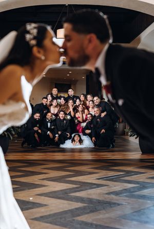 Wedding party poses together on geometric patterned floor for creative group photo during celebration.