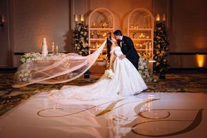A romantic wedding scene with a flowing long veil and elegant decor in a beautifully lit ballroom.