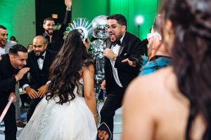 Wedding reception dance floor filled with guests celebrating under vibrant green lighting effects.