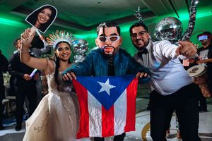 A group of people celebrate at a party with a Puerto Rican flag while dancing and socializing in green lighting.