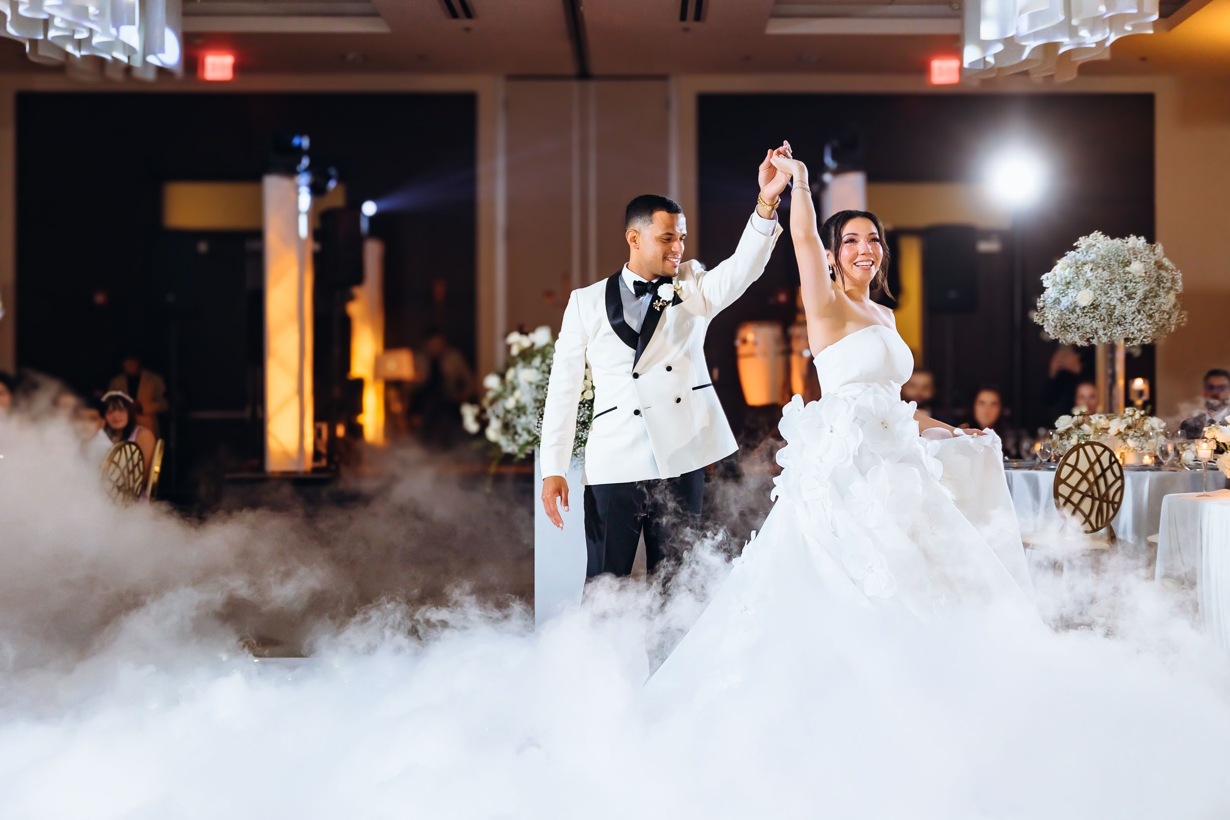 A couple dances together on a misty dance floor during their first dance at an elegant wedding reception.