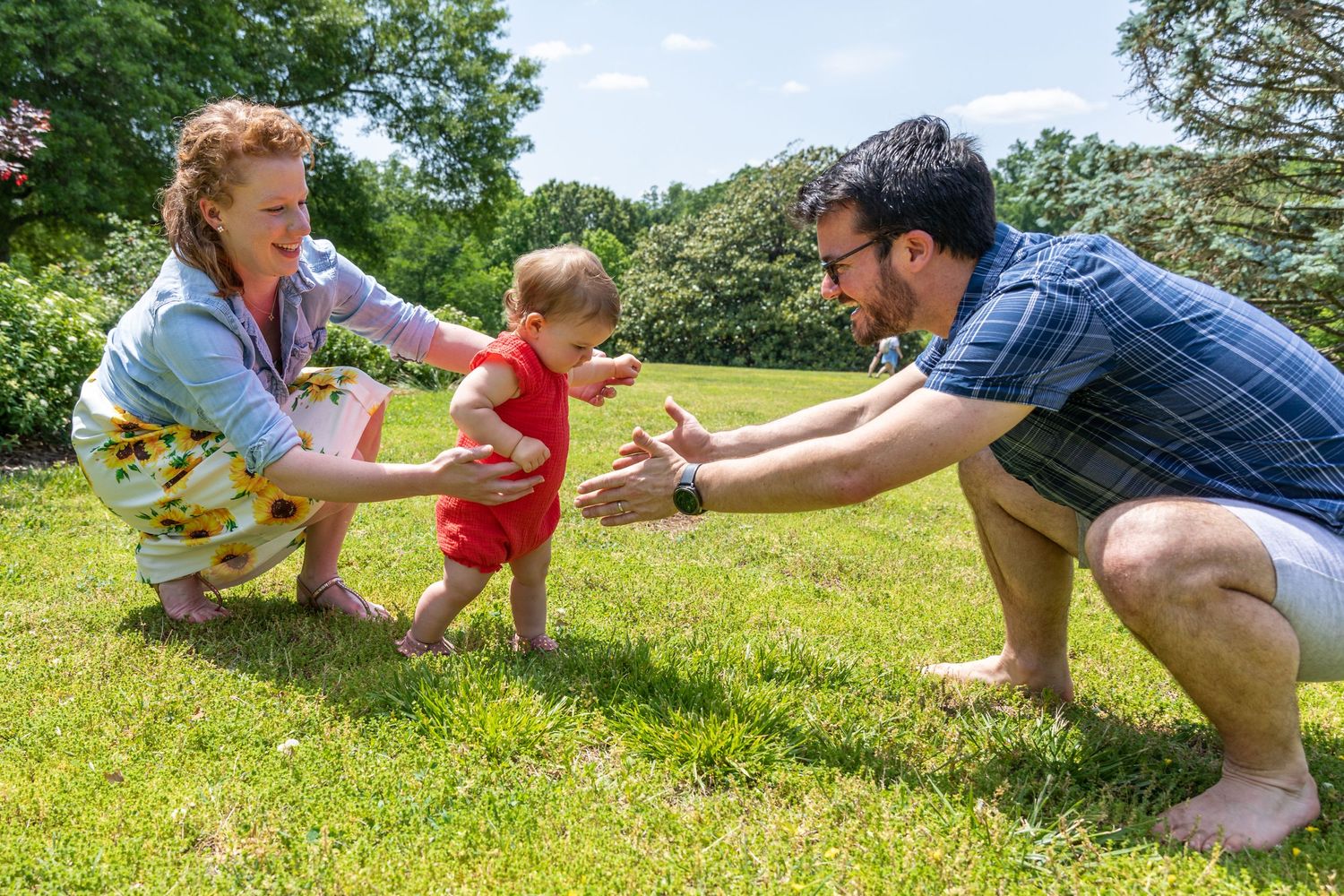 Family playing and running together on a sunny grassy hill during an outdoor photo session.
