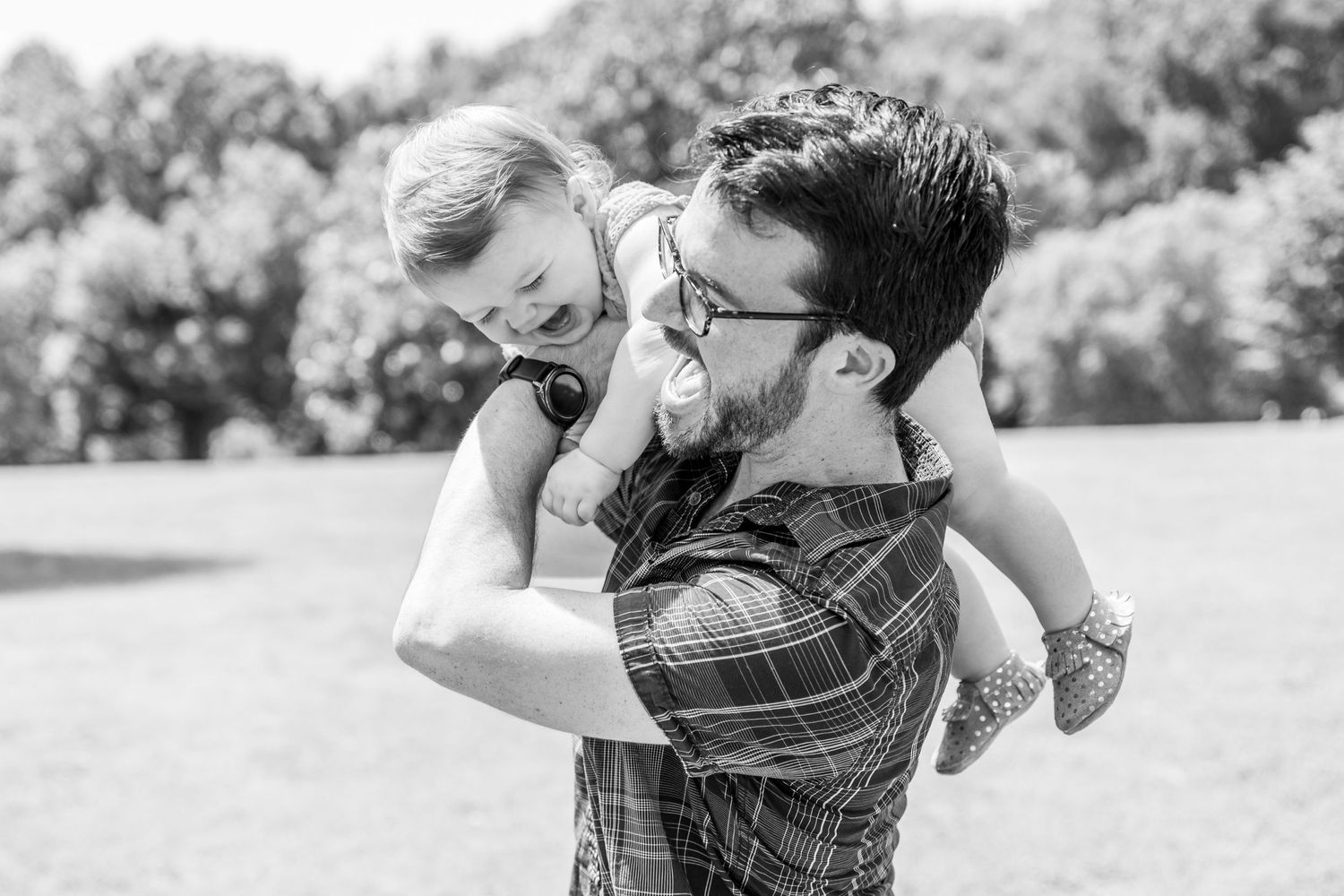 Black and white portrait of family members playing together outdoors.