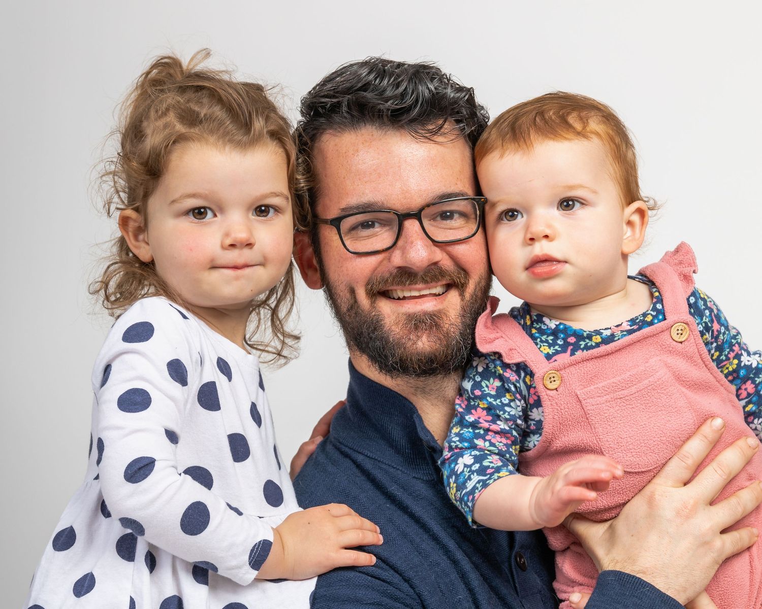 Family portrait with two children and parent against white background.