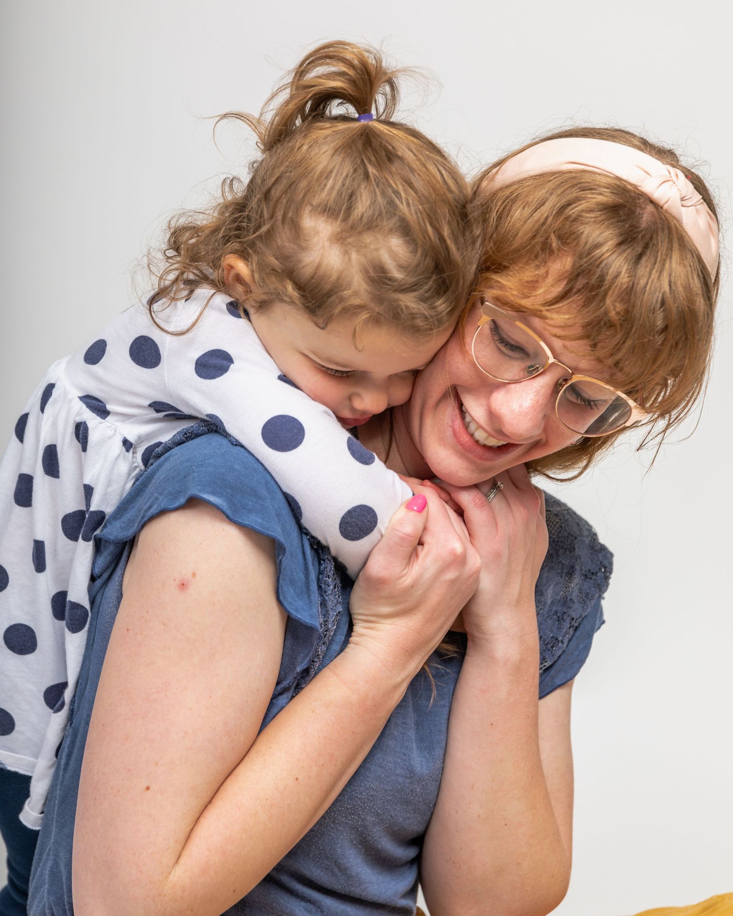 Playful moment captured between parent and child in polka dot dress.