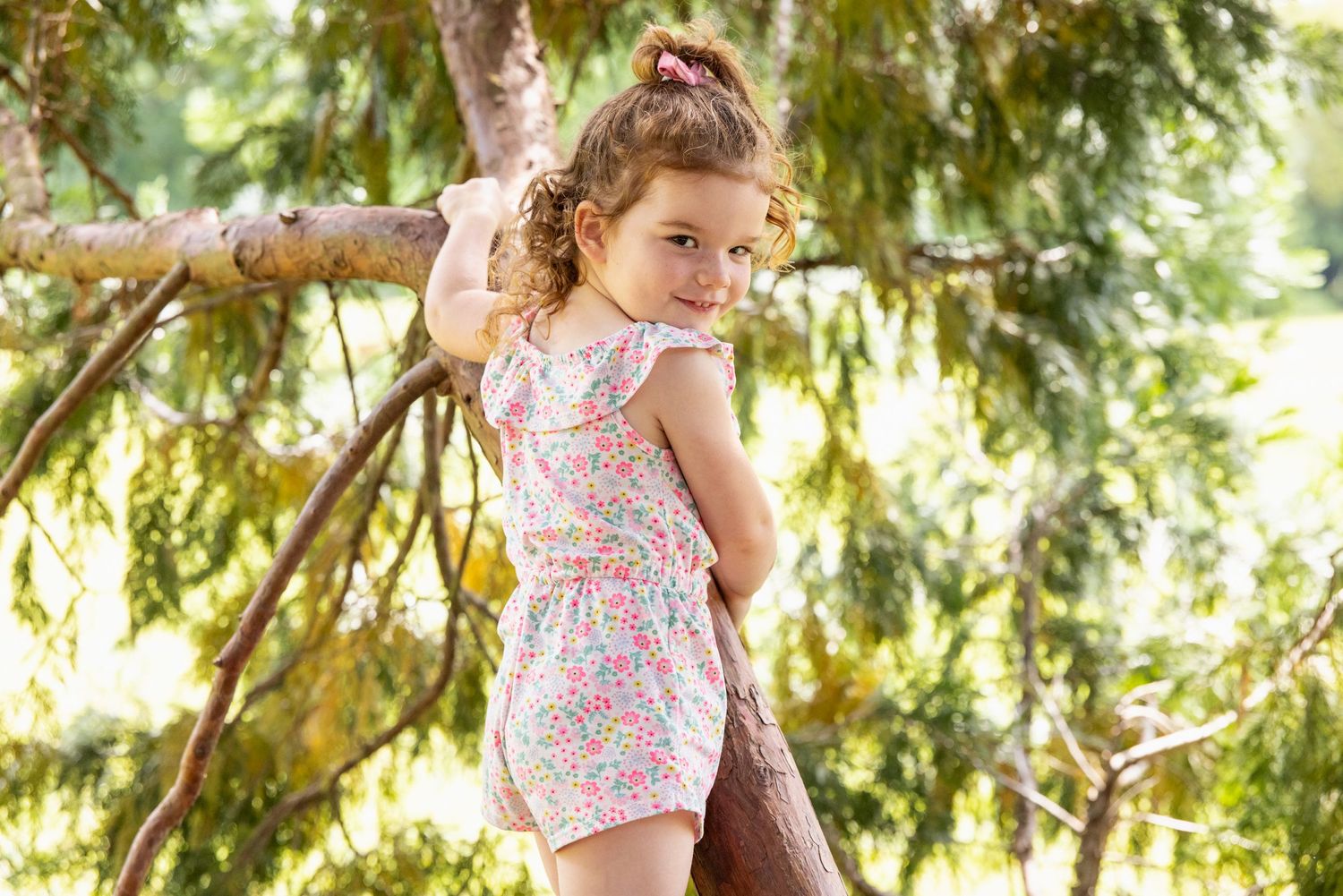 Children playing near a large tree branch in dappled sunlight.