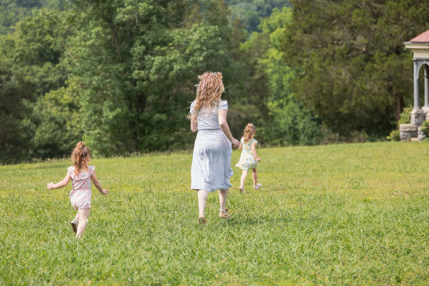 Family walking together across a sunny green field.