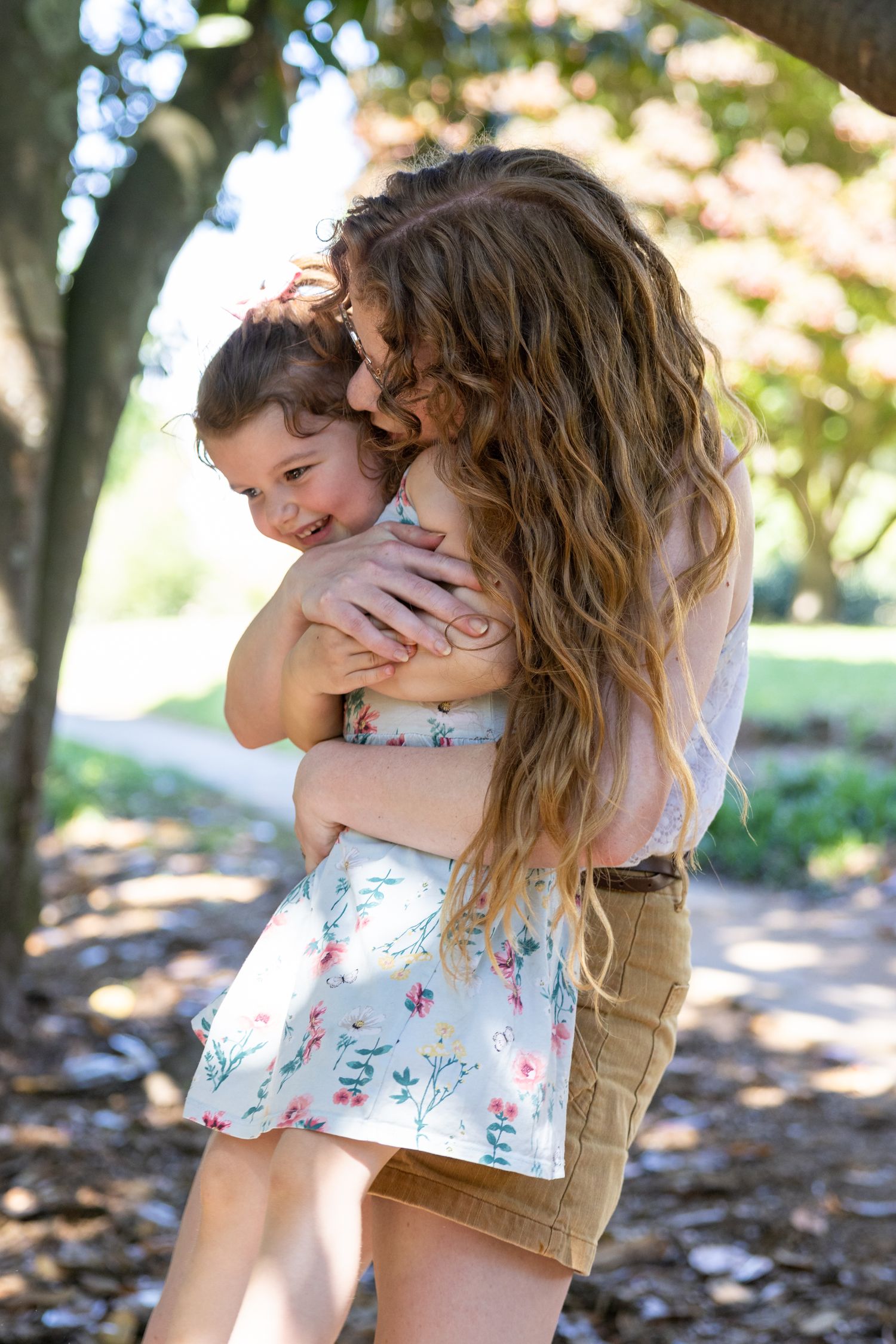 Tender embrace between parent and child on sunny outdoor path.