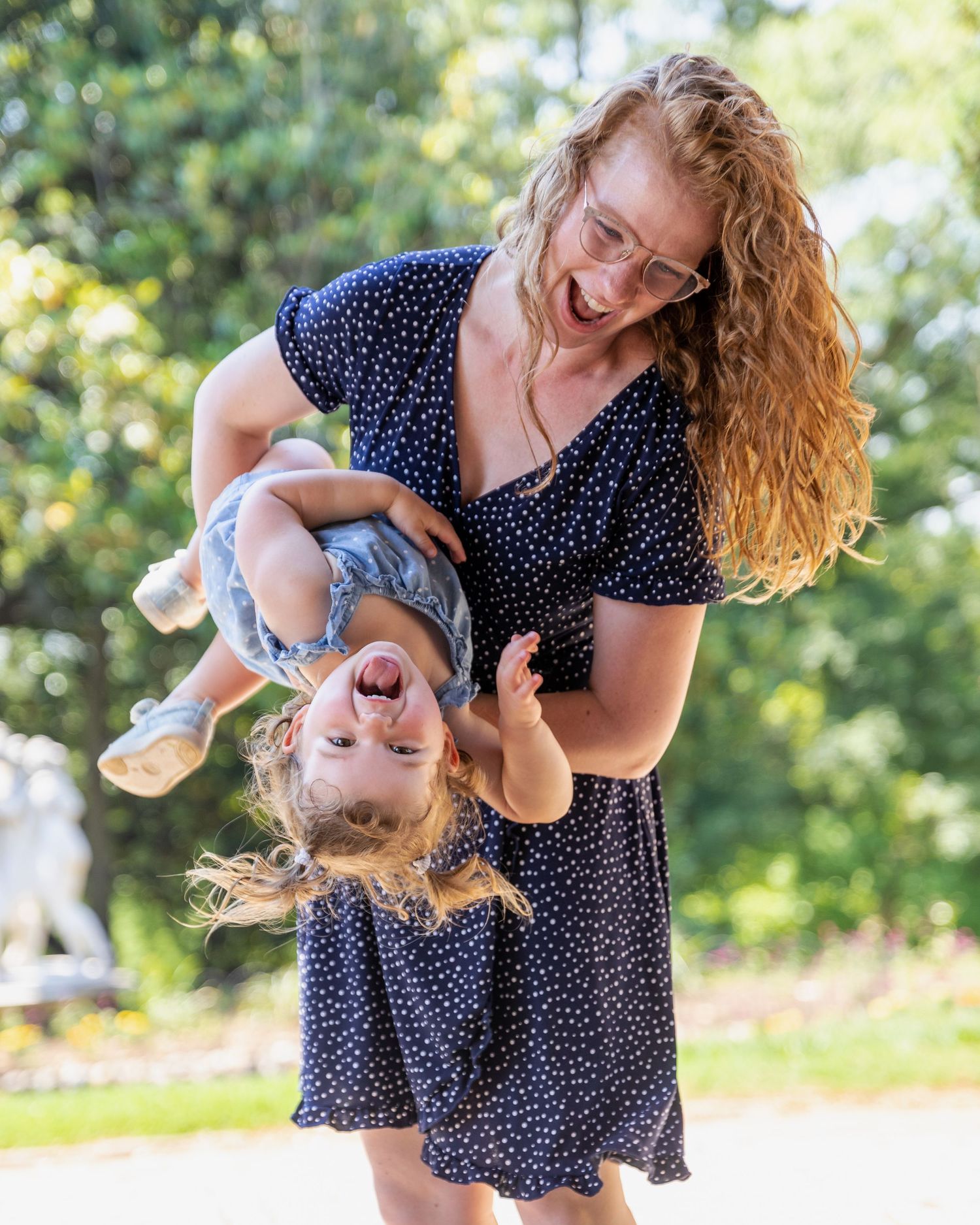 Playful outdoor scene with navy polka dot dress against sunny green background.