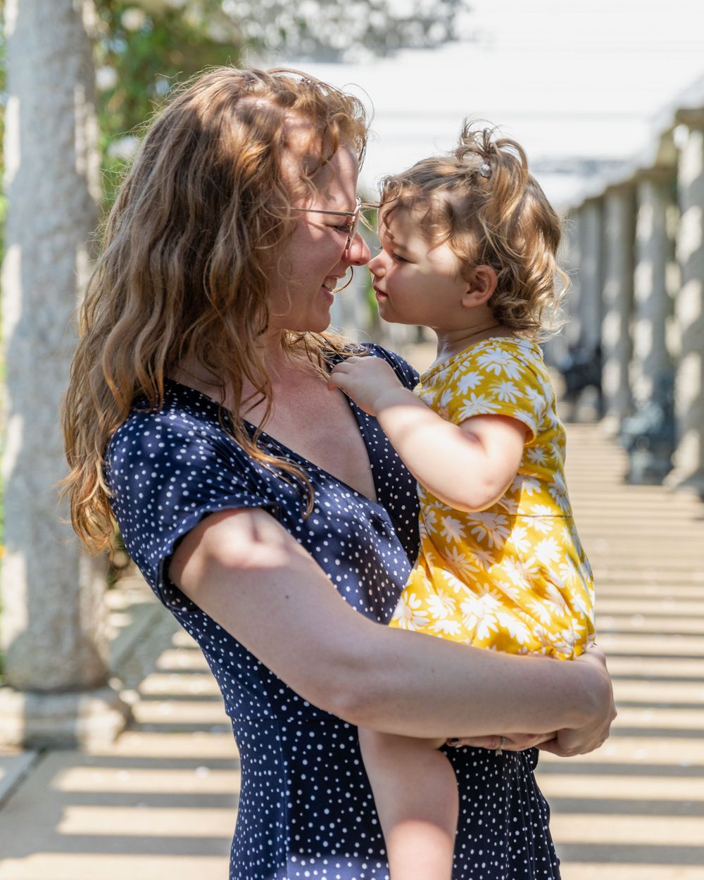 A joyful moment captured outdoors with polka dot dress and yellow floral outfit against a sunlit background.