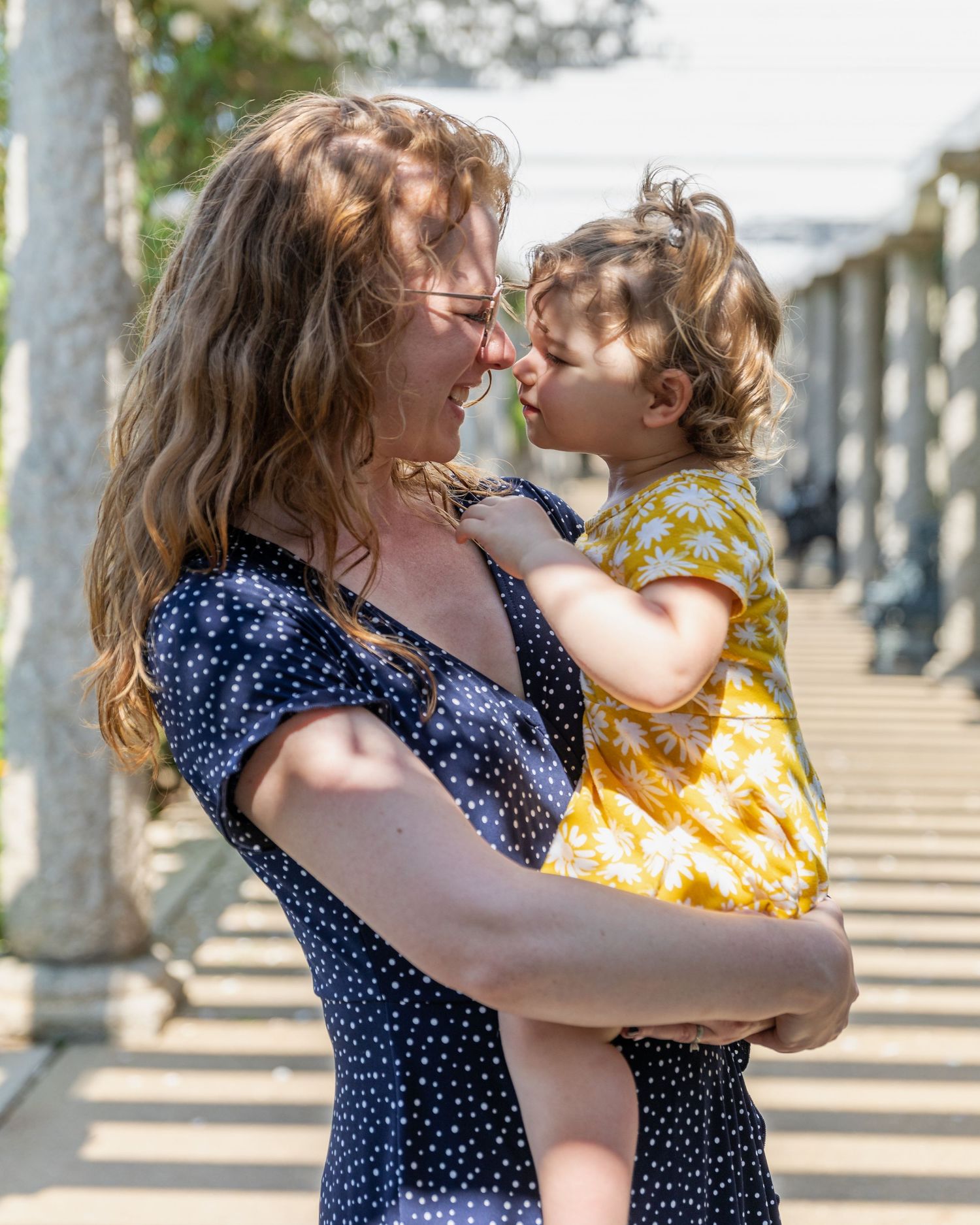 A joyful moment captured outdoors with polka dot dress and yellow floral outfit against a sunlit background.