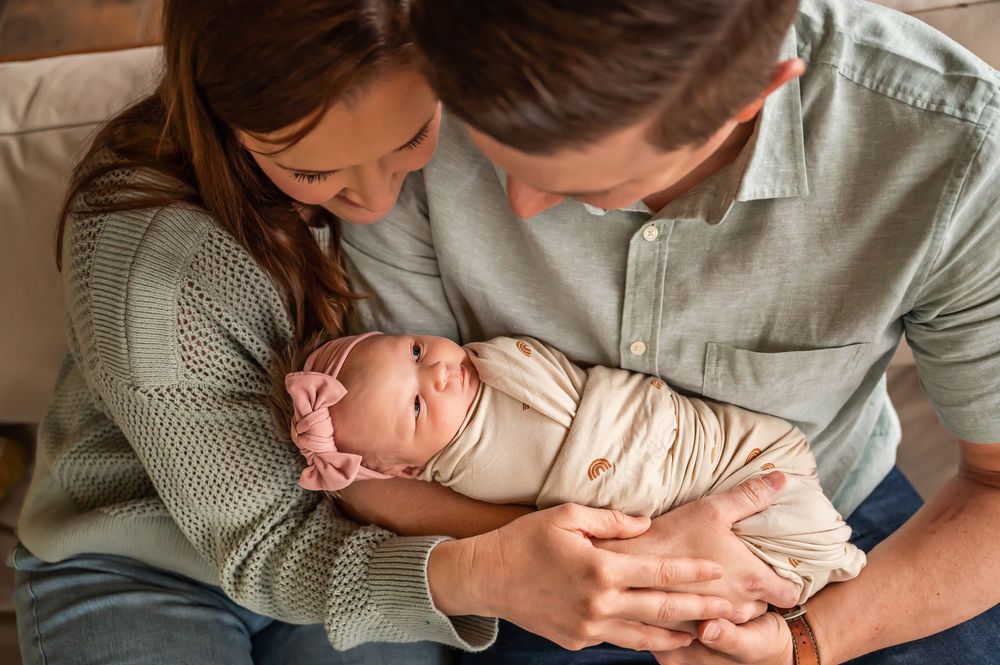 A collage of hands holding and gently cradling a newborn baby in soft knit clothing.