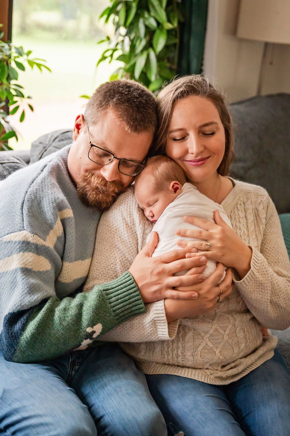 A couple in cozy sweaters share tender moments together on a couch in a series of intimate photographs.