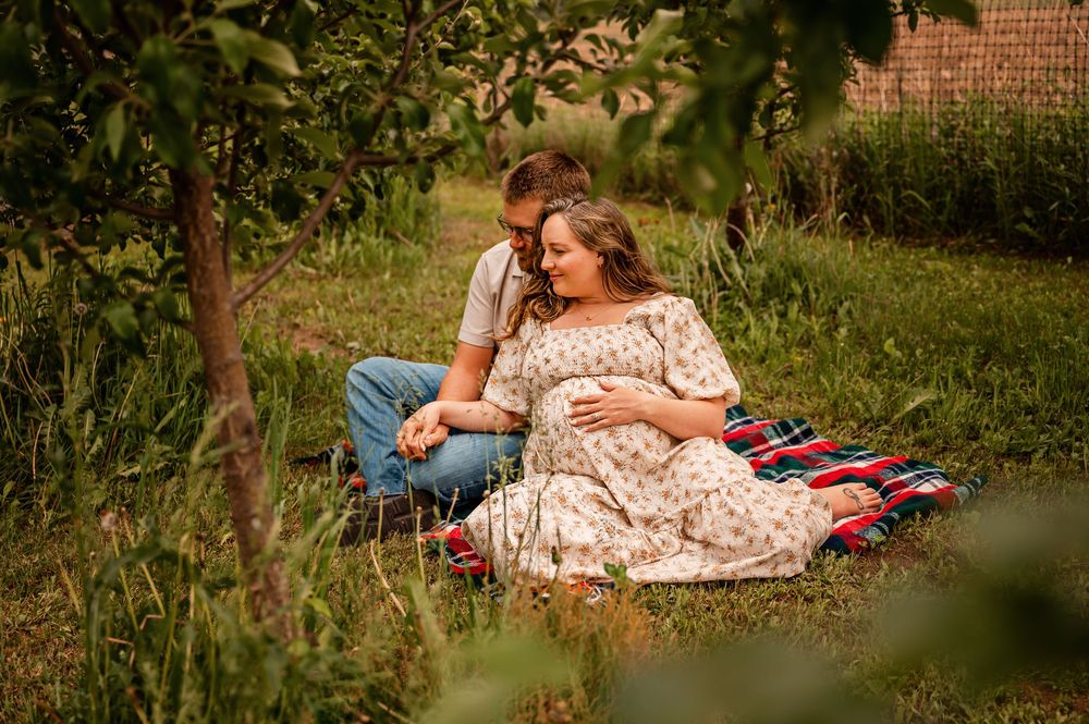 Family enjoying a relaxing summer picnic on a blanket in a lush green garden setting.