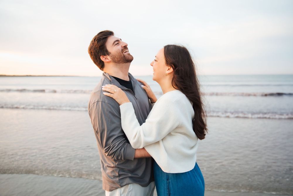 Romantic couple embracing on a beach at sunset, smiling at each other. Second Beach Middletown Rhode Island