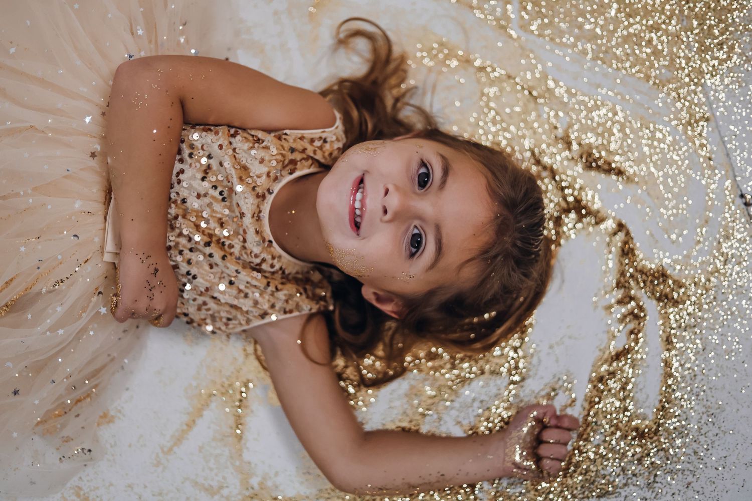 Glitter photography session with gold sparkles and tulle dress creating a magical effect. Custom photography