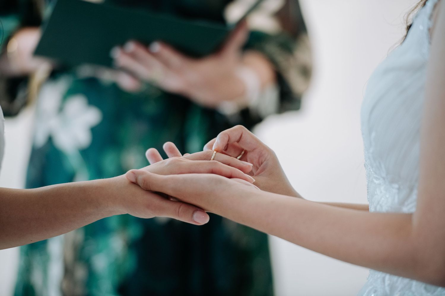 Close-up of hands exchanging rings during a wedding ceremony.