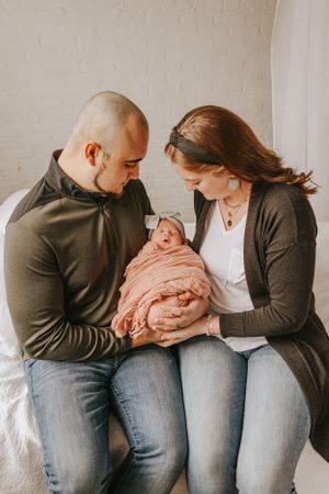 Natural family photos showing tender moments with newborn on white couch.