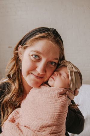 Sweet candid moments of parent bonding with newborn baby wrapped in pink muslin.