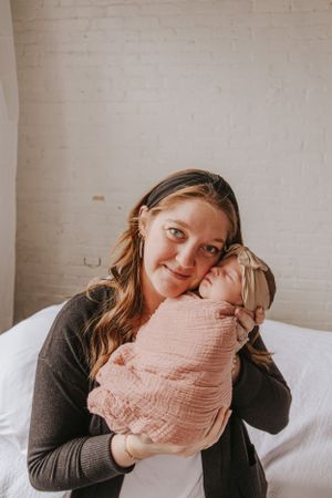 Intimate family photos showing gentle moments with a newborn wrapped in pink.