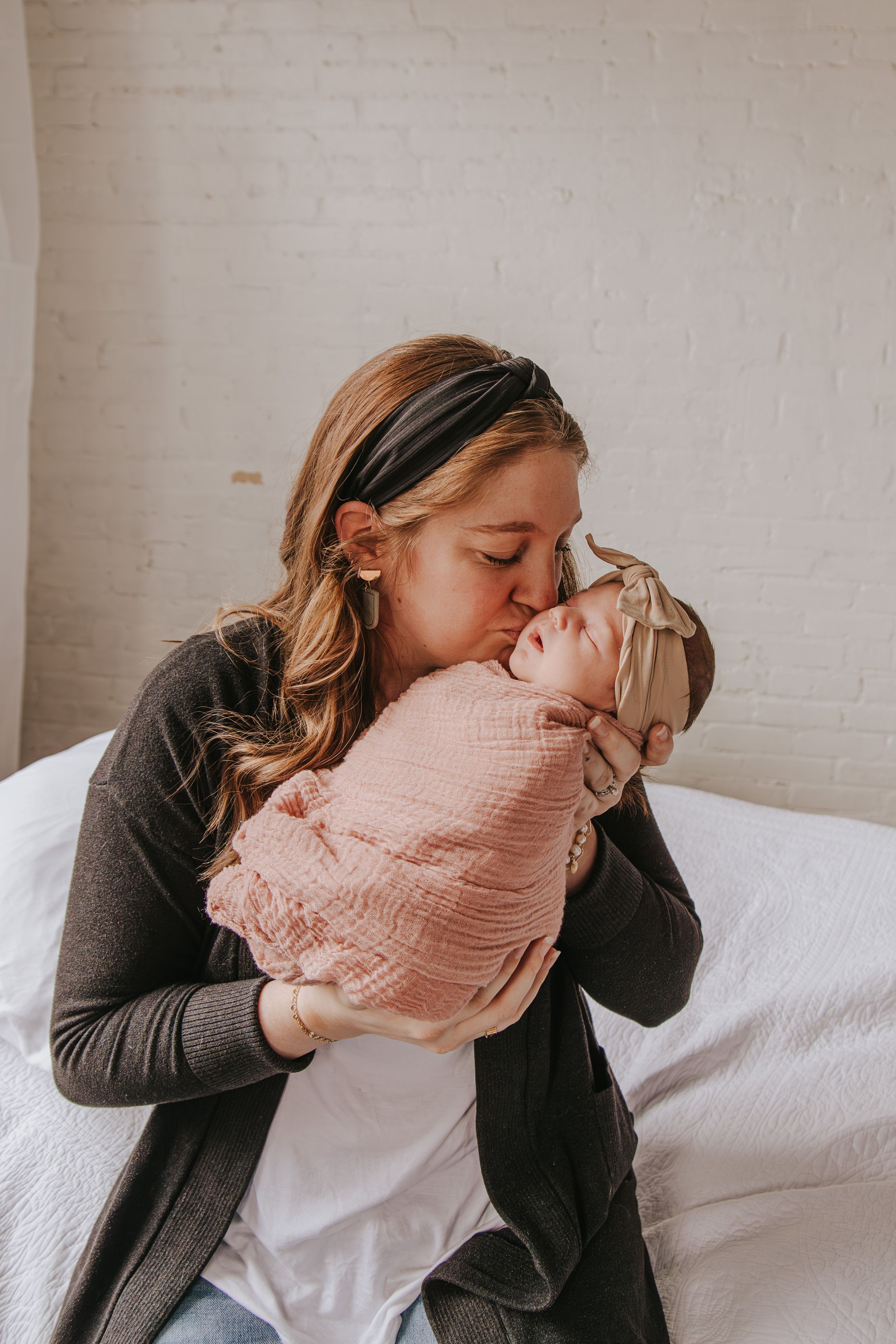 Parent sharing intimate bonding moments with newborn wrapped in pink swaddle.