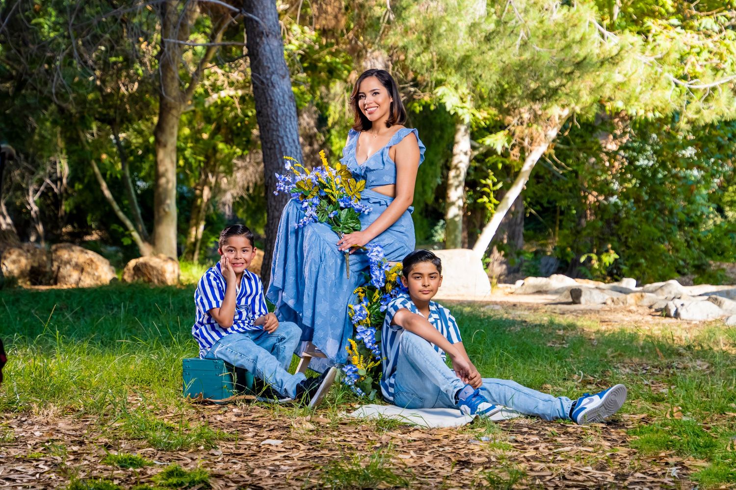 Family portrait in coordinated blue outfits relaxing in a park setting. chatsworth.
