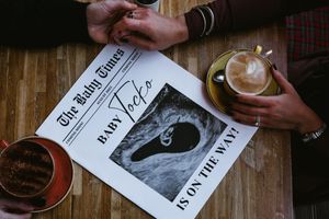 Hands flipping through pages of vintage photographs and documents on a rustic wooden table.