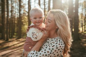 Two people in matching polka dot outfits share tender moments in a sunlit forest setting.