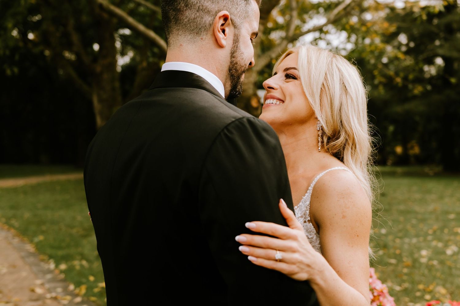 Romantic wedding couple embrace outdoors during golden hour.
